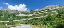 Carretera serpenteante en Grimselpass rodeada de vegetación alpina, no queda na!